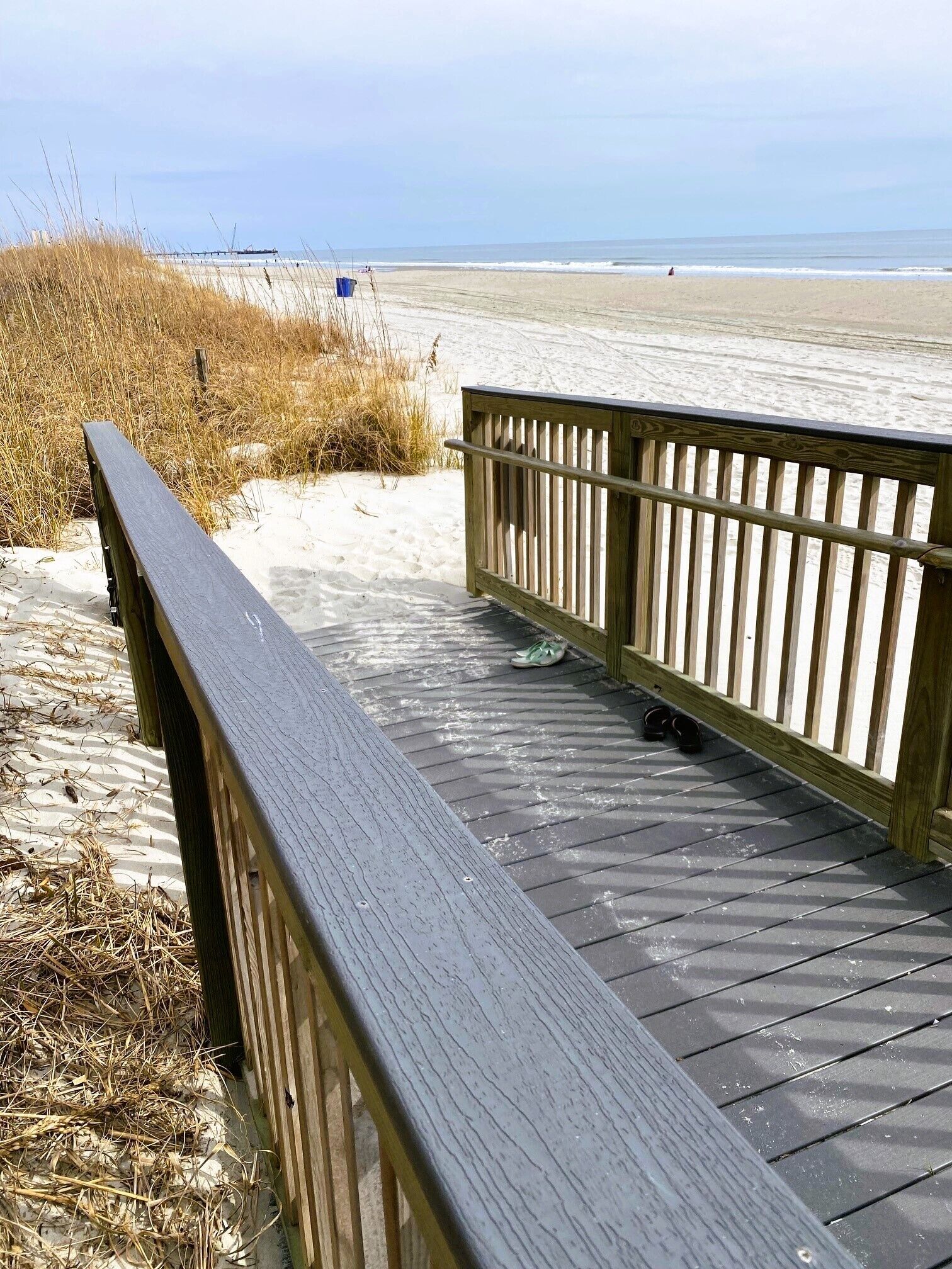 Une promenade en bois mène à une plage de sable, d’où l’on a une vue dégagée sur l’océan.