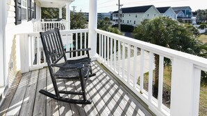 A wooden porch with white railings and two rocking chairs.