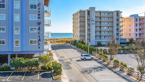 Ein mehrstöckiges Hotel mit Balkonen, einem Parkplatz und Blick auf den Strand.