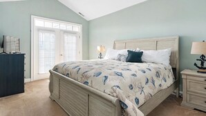Ein Schlafzimmer mit einem Bett, einem Schminktisch, einem Nachttisch und einem Fenster mit Jalousien.