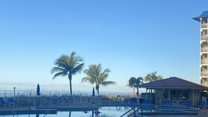 A pool area with lounge chairs and a building with a red roof. - Beach Front Condo (Bonita Springs)