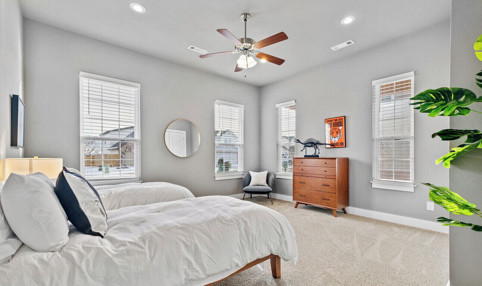 A bedroom with two beds, a dresser, a chair, and a ceiling fan.