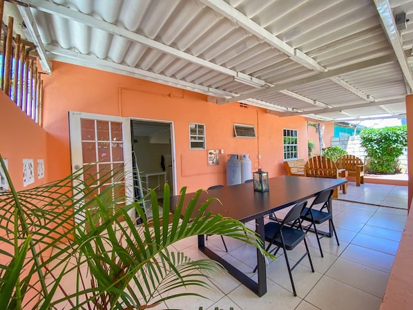 An indoor patio area with a table and chairs, a water dispenser, and a door leading to another room.