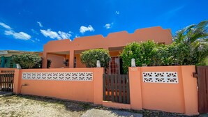 Uma casa com fachada cor de pêssego, entrada com portão e o número '503' no portão.