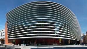 Un edificio moderno dalle linee curve e lunghe file orizzontali di finestre.