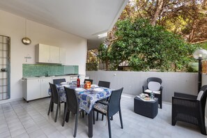 A modern outdoor dining area with a table set for six, surrounded by wicker chairs.