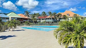 A resort with a swimming pool, palm trees, and colorful buildings.