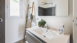 A bathroom with a large mirror, a sink, a towel rack, and a window.