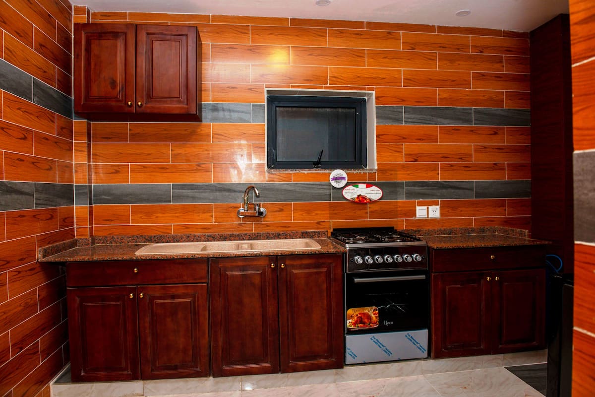 Una cocina con armarios de madera, encimera de granito, horno empotrado y una ventana sobre el fregadero.