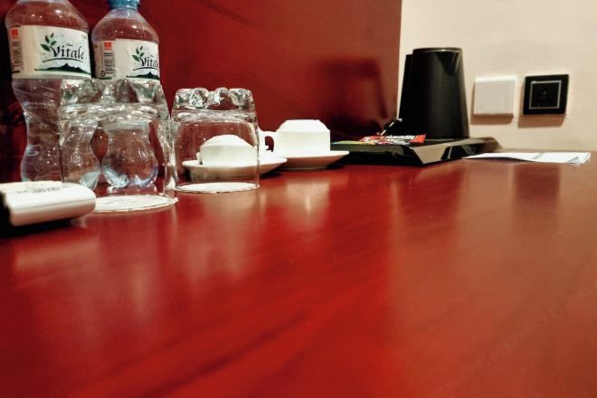 A wooden table with a coffee maker, two bottles of water, and a glass.