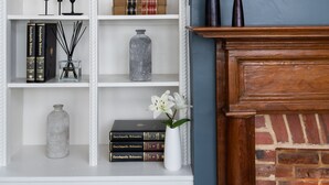 Una estantería con libros, objetos decorativos y una chimenea.