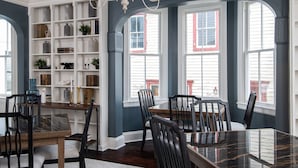 Comedor con una gran mesa rectangular, seis sillas, una araña y una estantería empotrada con diversos objetos decorativos.