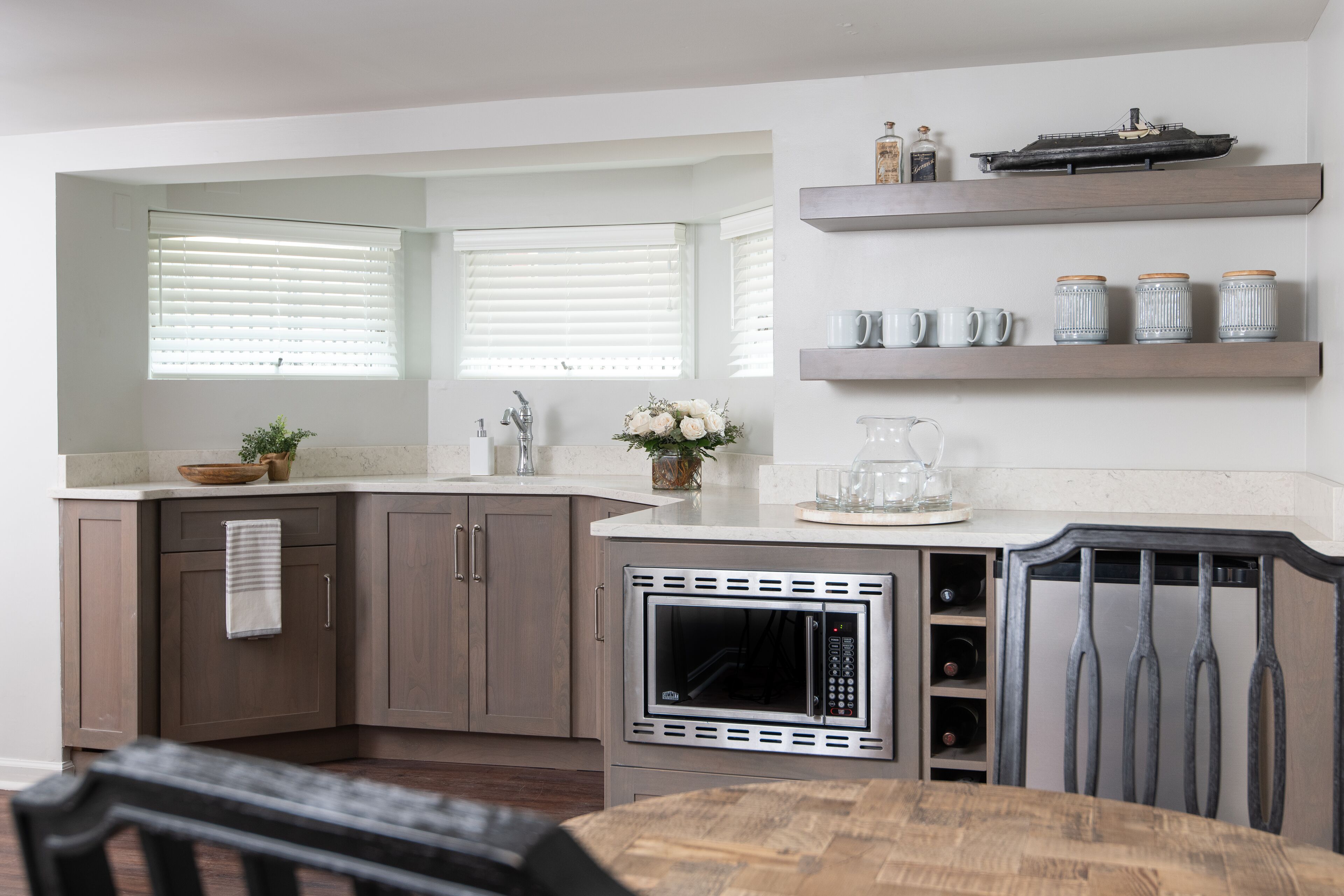 A modern kitchen with a built-in microwave, wooden cabinets, and a dining area with a table and chairs.
