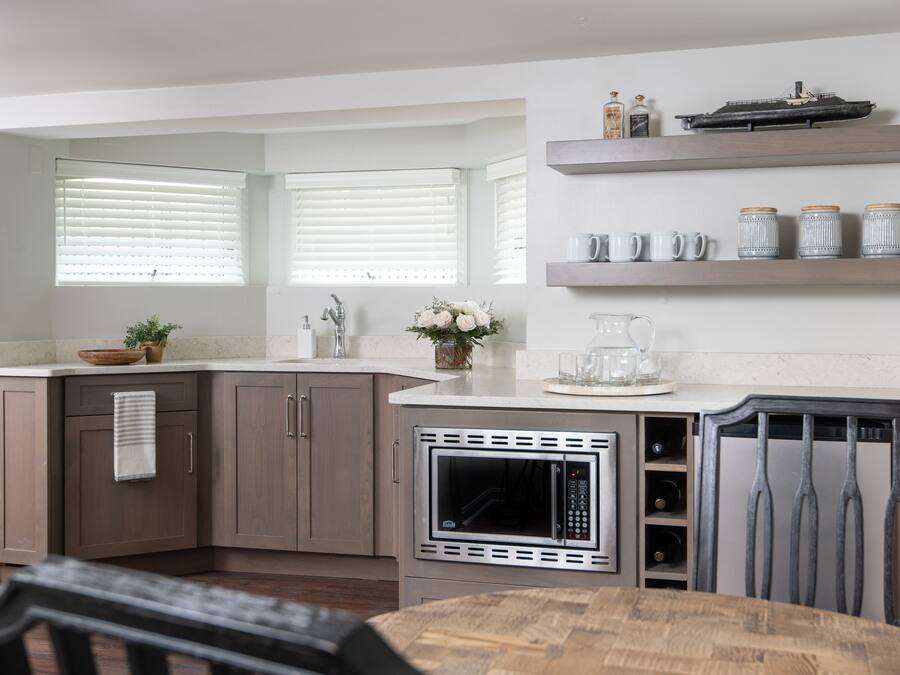 A modern kitchen with a built-in microwave, wooden cabinets, and a dining area with a table and chairs.