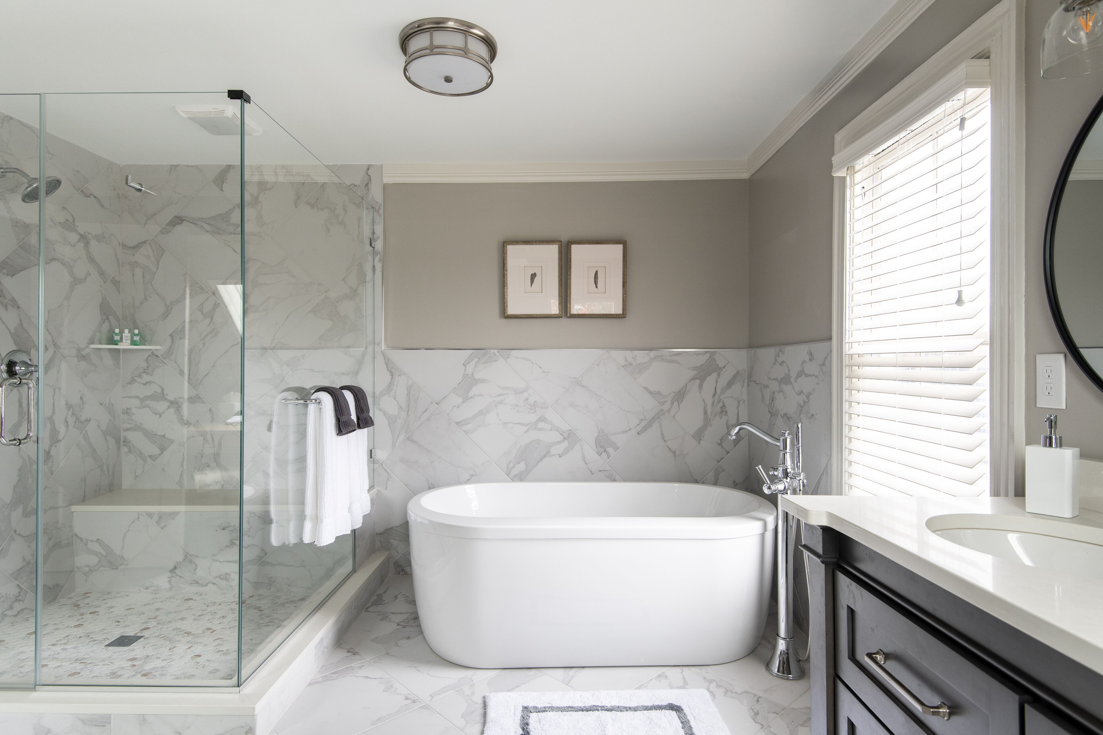 A modern bathroom with a glass-enclosed shower, a freestanding bathtub, and a vanity with a mirror.
