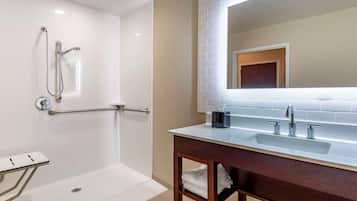 Un bany modern amb plat de dutxa, un lavabo amb mirall i un rentapans.