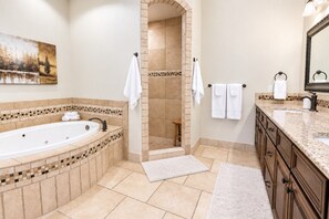 A bathroom with a bathtub, shower, and vanity with a mirror. - Comfortable condo with indoor/outdoor pool (Hurricane)