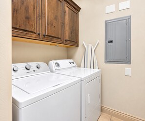 A laundry room with two white washing machines, wooden cabinets, and a grey utility cabinet. - Comfortable condo with indoor/outdoor pool (Hurricane)