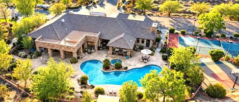 A residential property with a swimming pool, multiple outdoor seating areas, and a landscaped garden.