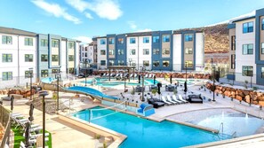A hotel pool area with multiple pools, lounge chairs, and a mountainous backdrop.