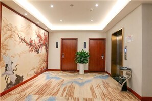 A hotel lobby with a large mural, two wooden doors, a potted plant, and an elevator. - Bofei Hotel (Chongqing)