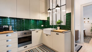 A modern kitchen with a green tiled backsplash, stainless steel appliances, and a wooden countertop.