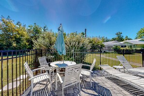 Relax on the patio with comfortable seating and a shaded area overlooking a serene grassy landscape.