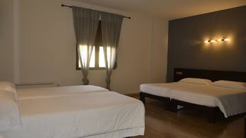 Habitación de hotel con dos camas individuales, una ventana grande con cortinas, una lámpara de pared y piso de madera.