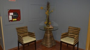 Ein Zimmer mit zwei Korbstühlen, einem Glastisch und einer Blumenvase.