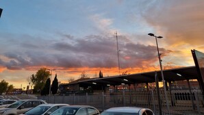 Un estacionamiento con coches y un edificio con zona techada.