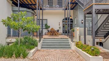 A courtyard with brick flooring, a central staircase, and a seating area with outdoor furniture.