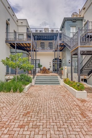 A courtyard with brick flooring, a central staircase, and a seating area with outdoor furniture.
