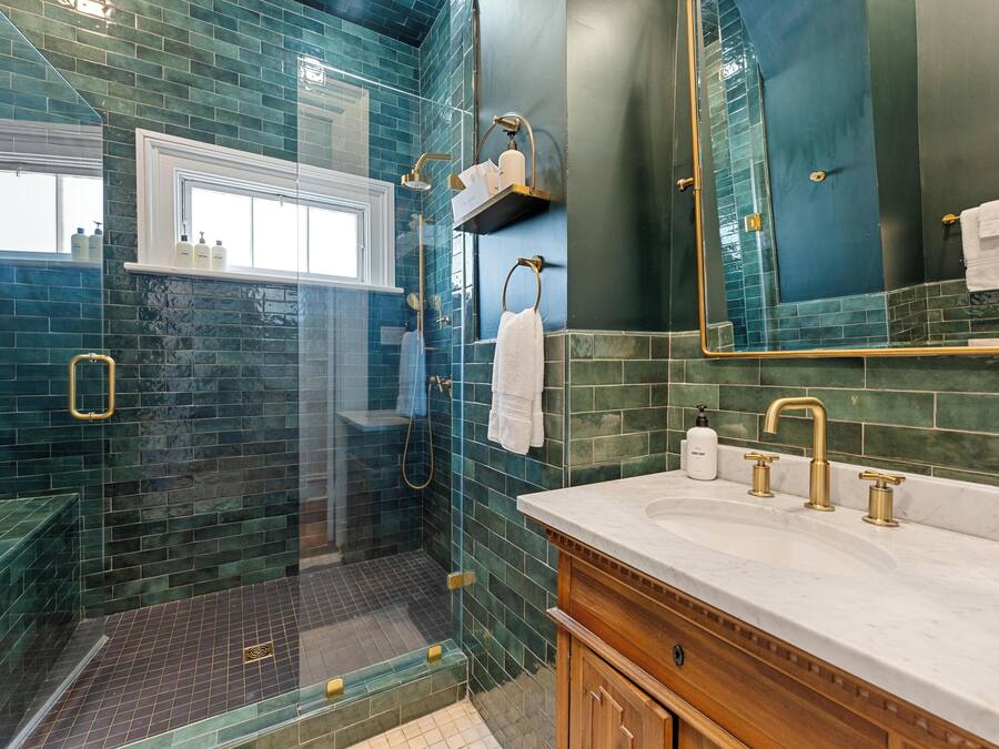 A bathroom with a glass-enclosed shower, a vanity with a sink, and a mirror.