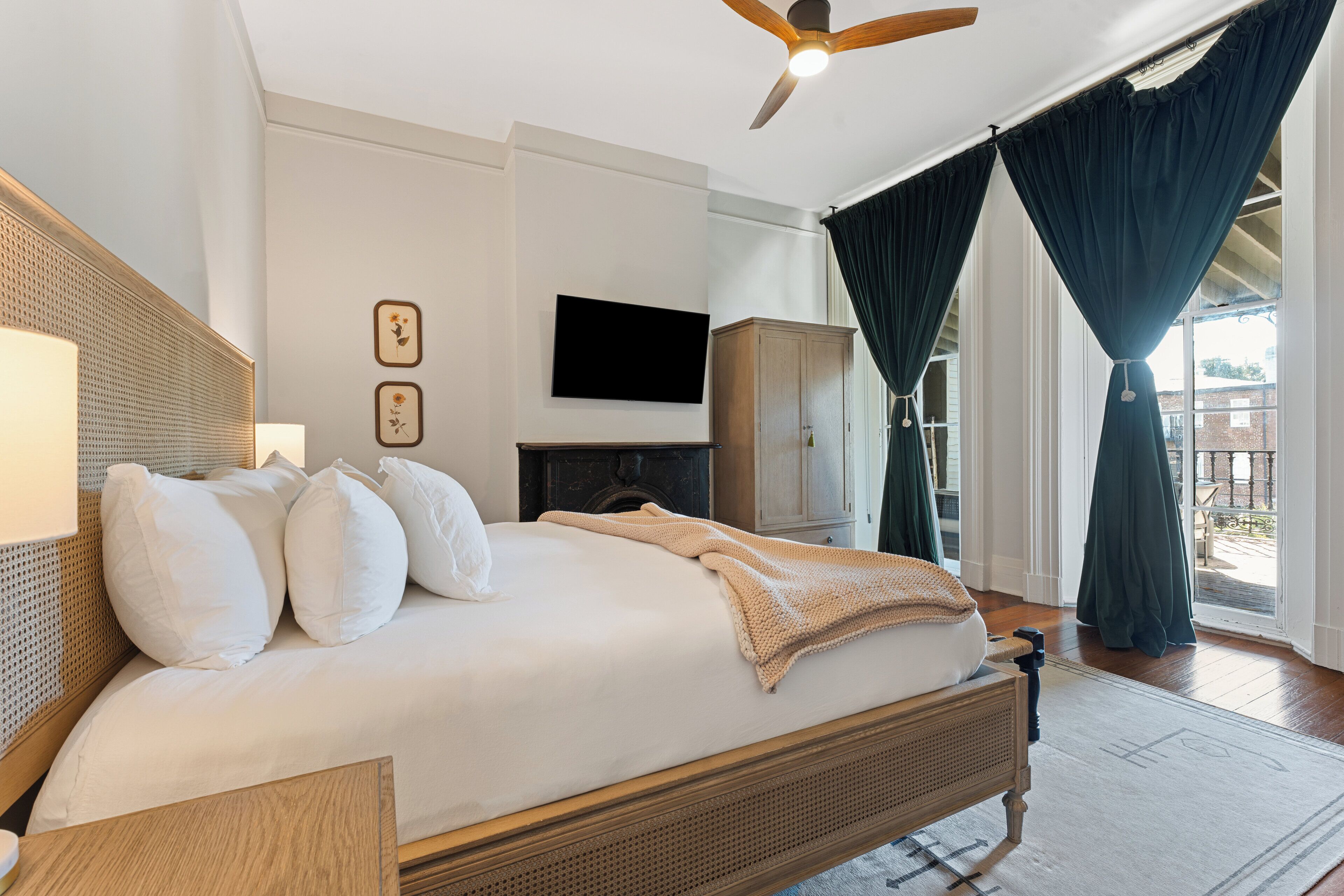 A bedroom with a bed, a television, a wardrobe, and a ceiling fan.