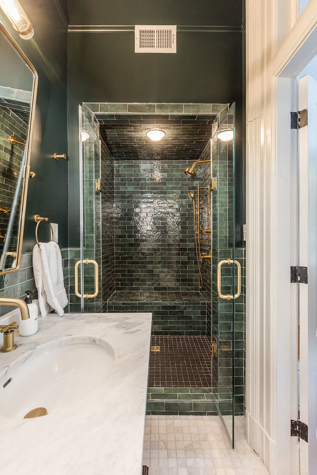 A modern bathroom with a glass-enclosed shower, a marble sink, and a large mirror.