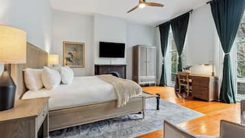 A spacious bedroom with a large bed, a desk, a wardrobe, and a television.