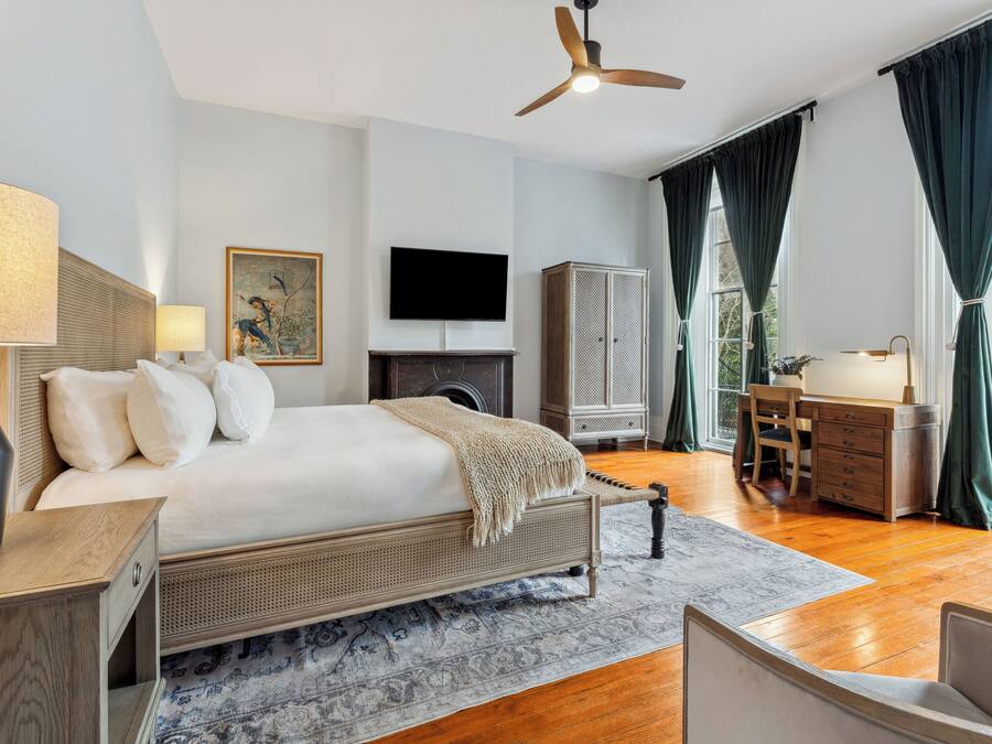 A spacious bedroom with a large bed, a desk, a wardrobe, and a television.