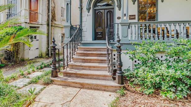 A historic building with a grand entrance, a staircase leading to the door, and a balcony with a railing. - Bellwether House (Savannah)