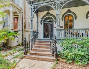 A historic building with a grand entrance, a staircase leading to the door, and a balcony with a railing.