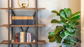 Una habitación con una estantería, una planta en maceta y un sofá gris.