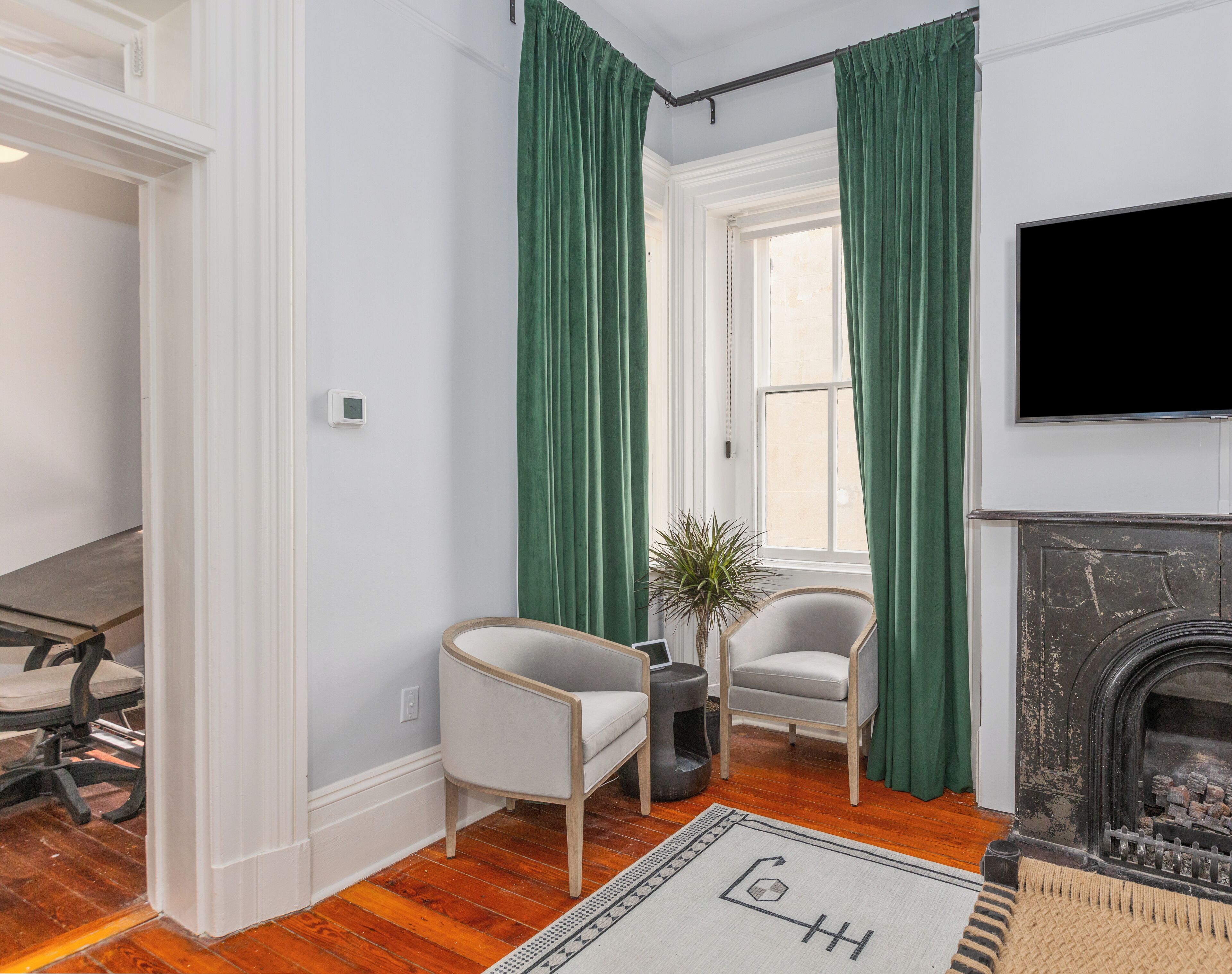 Una sala de estar con chimenea, dos sillones, una mesa de centro y un televisor montado en la pared.