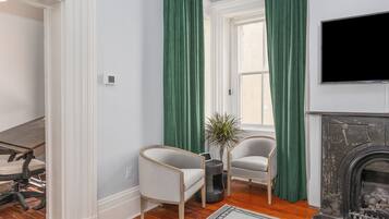 Una sala de estar con chimenea, dos sillones, una mesa de centro y un televisor montado en la pared.