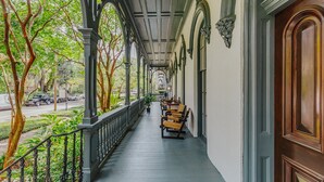 A covered porch with wooden benches, a railing, and a view of the street. - Bellwether House (Savannah)