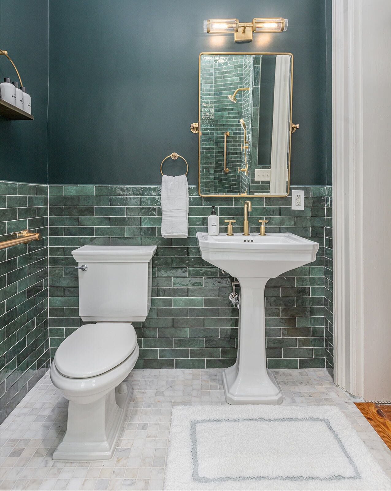 A bathroom with a white toilet, a pedestal sink, and a large mirror.