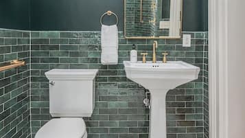A bathroom with a white toilet, a pedestal sink, and a large mirror.