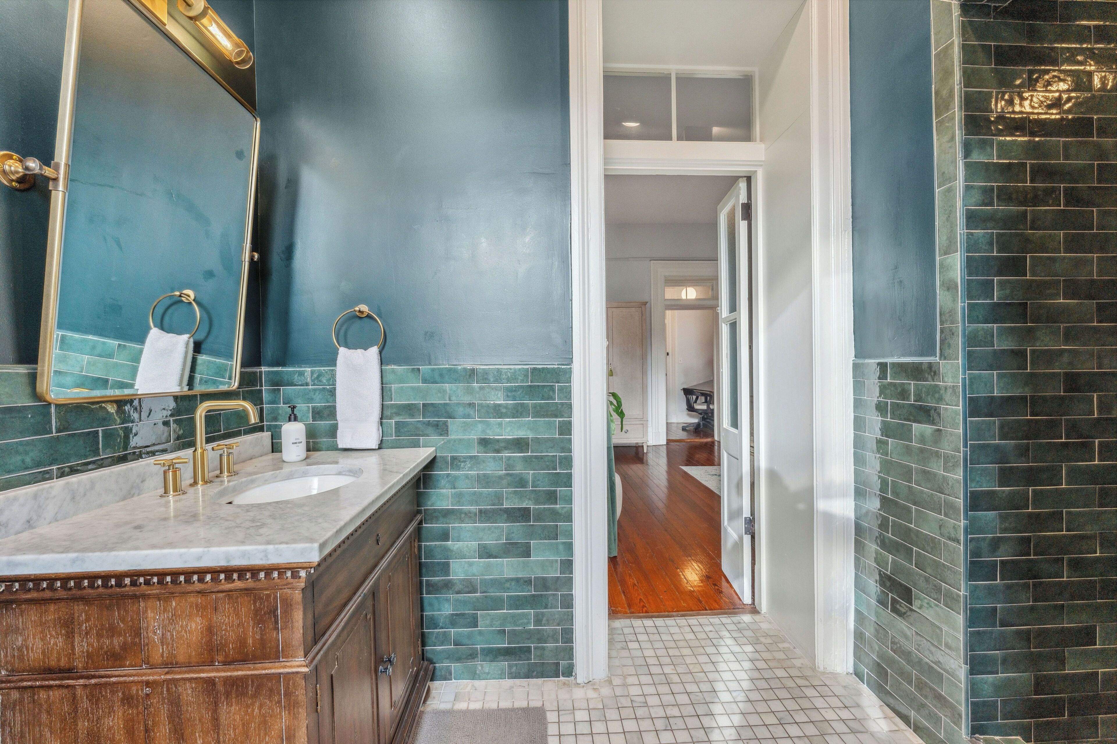 A bathroom with a large mirror, two sinks, and a wooden vanity.