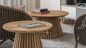 Una sala moderna con una mesa redonda de madera, un sofá y un televisor sobre un mueble.