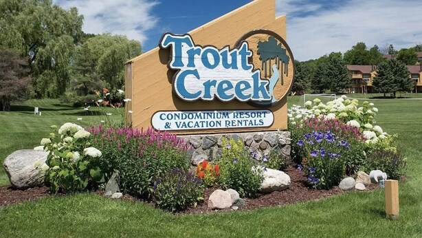 A sign for Trout Creek Condominium Resort & Vacation Rentals with a landscaped garden in the foreground.