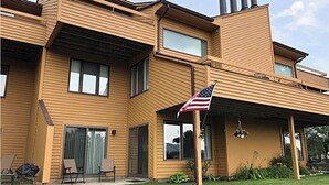 A modern two-story house with a flat roof, large windows, and an American flag.
