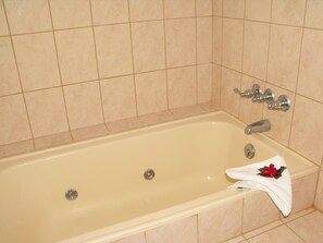 Bathroom features a bathtub with two faucets and a single drain, surrounded by tiled walls.